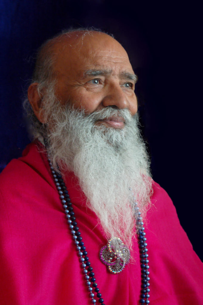 Swami Shyam wearing a silk magenta poncho in profile